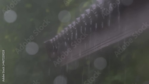 Blurry scene of rain falling and flowing from eaves of a house, raining and bokeh. Rain water flowing down from the roof.