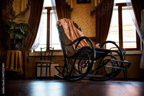 antique armchair with a plaid in the office against the background of the windows of an old house
