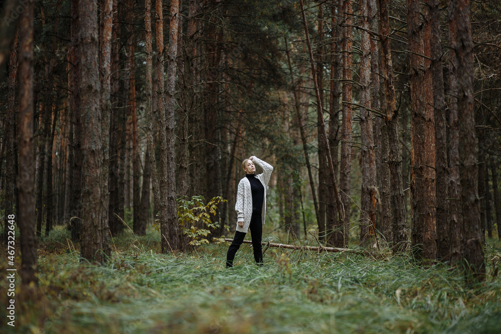 girl in a gray cape and black dress among the autumn forest