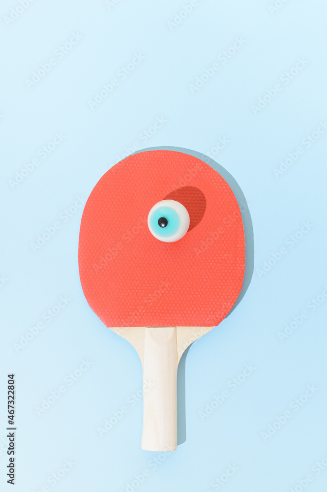 A table tennis racket with a false eye instead of a ball. Surreal sport ping pong competitive concept. A table tennis racket with a false eye instead of a ball. Surreal sport ping pong competitive concept.