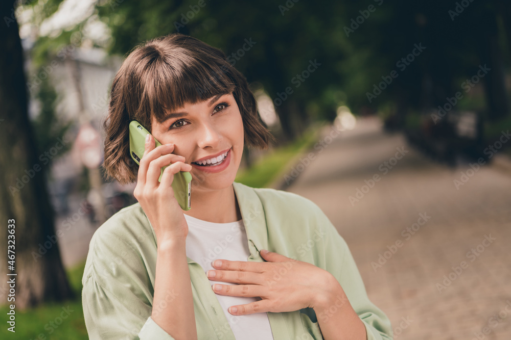 Portrait of attractive cheerful carefree brown-haired girl talking on phone discussing spending time in forest outdoors