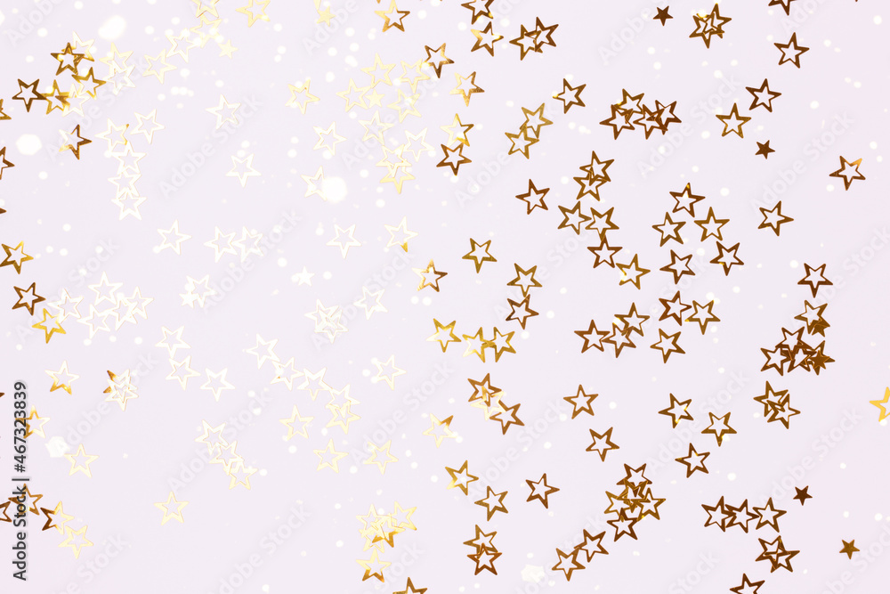 Metallic gold colored glittering stars confetti scattered on a white background.
