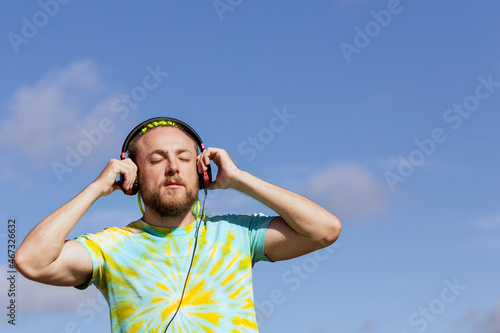 A man with an interesting mohawk hairstyle stands on the bridge and puts on headphones