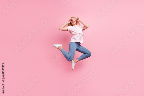 Full size photo of funky millennial blond lady jump wear spectacles t-shirt jeans sneakers isolated on pink background © deagreez