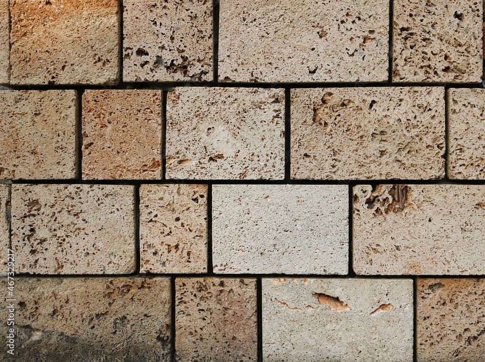 Naklejka premium solid square brickstones from the wall of a fortress - closeup surface of yellow stone bricks texture background