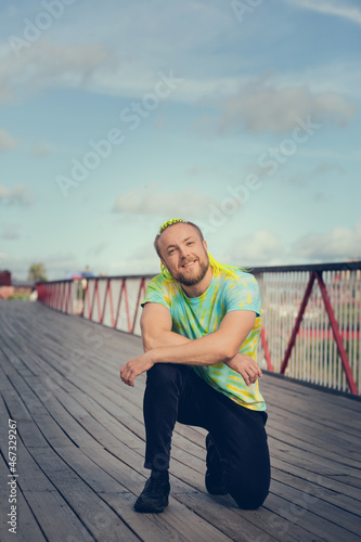 Fototapeta Naklejka Na Ścianę i Meble -  A man with an interesting mohawk hairstyle stands on the bridge