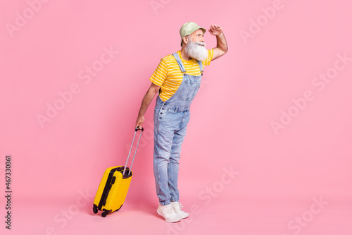Full length body size view of attractive focused man carrying bag looking far away isolated over pink pastel color background