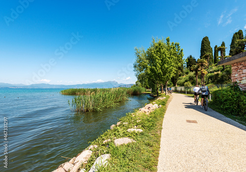 Pedestrian and bicycle lane on the coast of Lake Garda that connects the towns of Lazise, Cisano, Bardolino and Garda. Verona province, Veneto, Italy, Europe. On the horizon the coast of Lombardy.