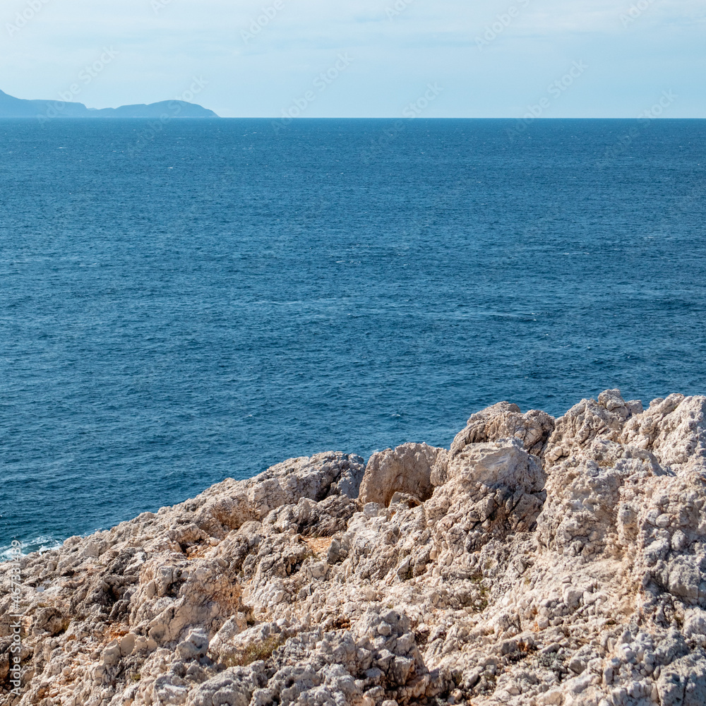Rocky steep cliff close view on blue vivid Ionian seascape background. Summer nature in Lefkada island, Greece Rocky steep cliff close view on blue vivid Ionian seascape background. Summer nature in Lefkada island, Greece