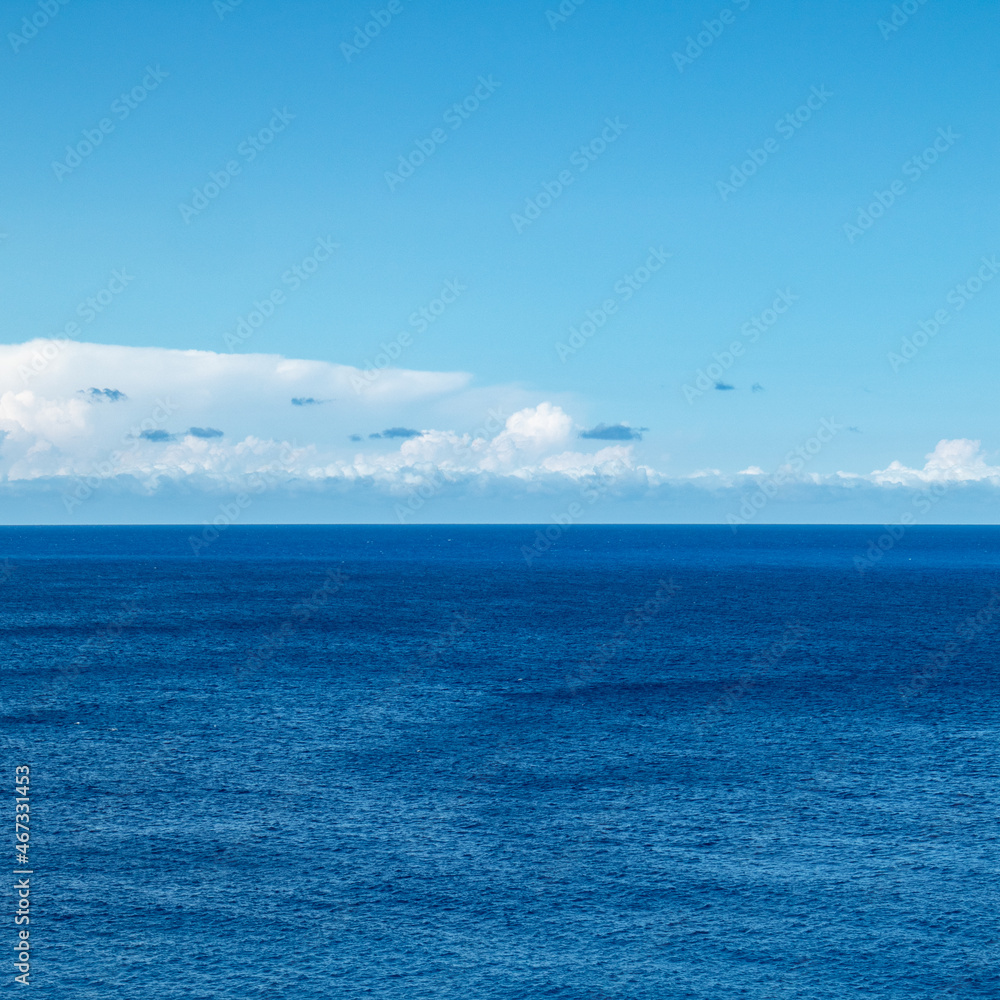 Blue Ionian sea landscape and skyscape view in Greece. Bright day with low scenic clouds over rippled deep blue water surface