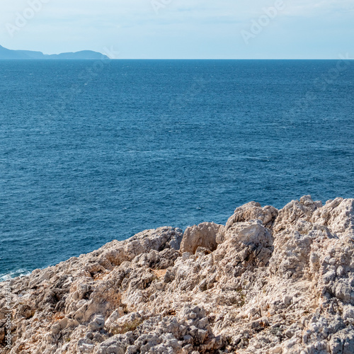 Rocky steep cliff close view on blue vivid Ionian seascape background. Summer nature in Lefkada island, Greece