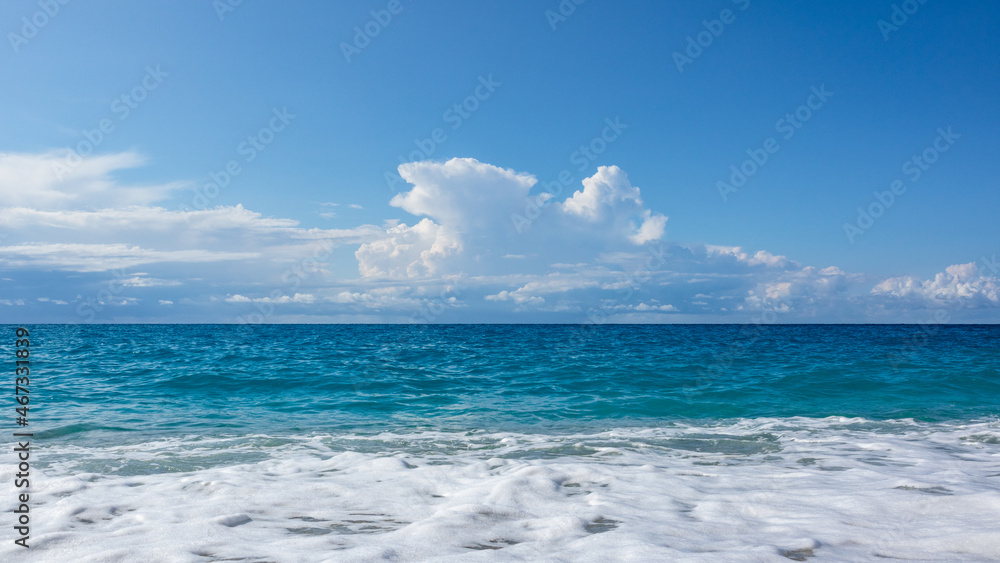 Obraz premium Scenic blue stormy waves and white foam with epic cloudscape on coast of Lefkada island in Greece. Summer nature vacation travel to Ionian Sea