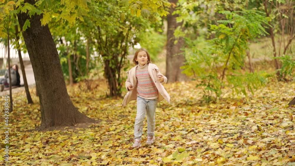 a cute little girl runs through the autumn park with chestnuts in her hands. a cute little girl runs through the autumn park with chestnuts in her hands.