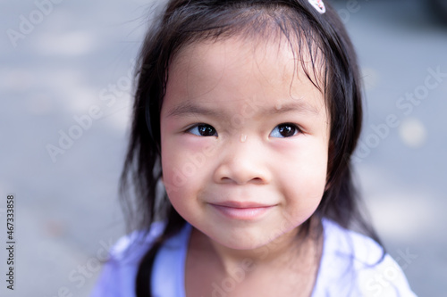 Close up of little girl's face was sweating due to the hot weather. Cute child sweet smiled.