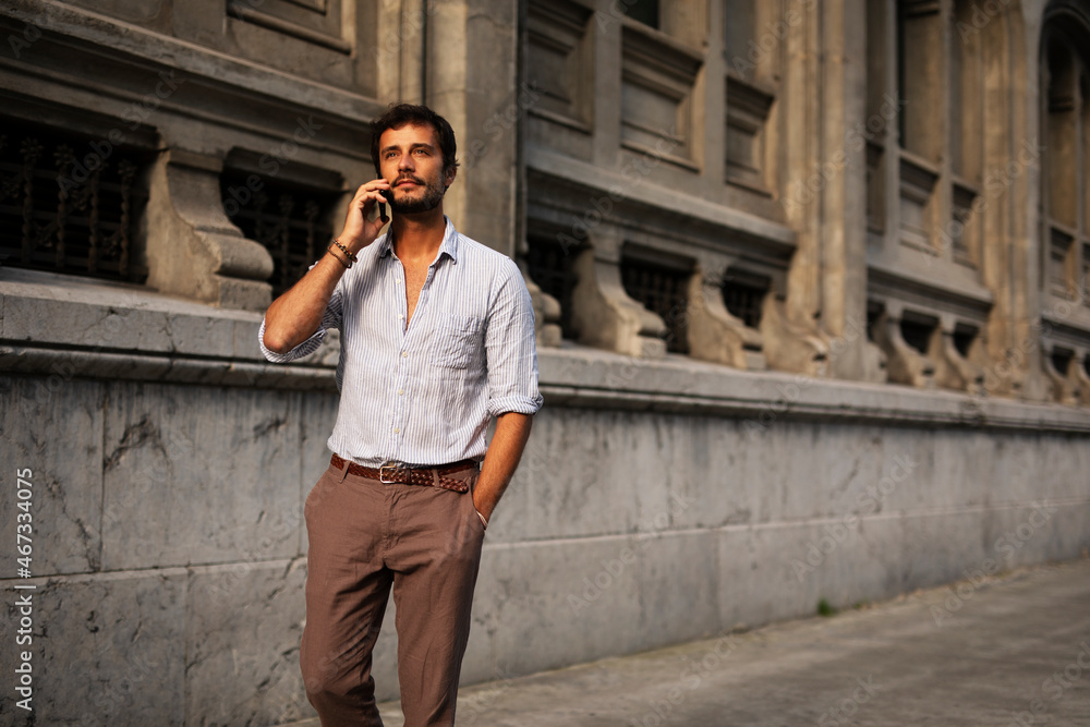 Young stylish man using the phone outdoors. Fashion happy man talking to the phone. Young stylish man using the phone outdoors. Fashion happy man talking to the phone.