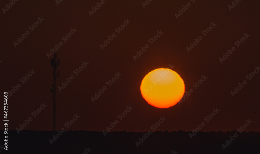 Beautiful orange rising sun in the morning sky, heat in the atmosphere, climate change concept Beautiful orange rising sun in the morning sky, heat in the atmosphere, climate change concept