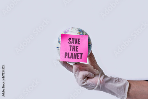 Hand in medical gloves holds a globe with note - save the planet over white background