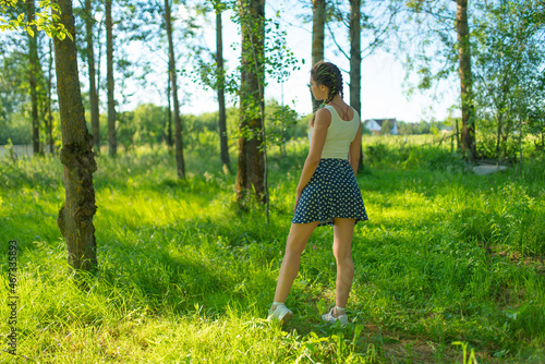 A girl in a skirt and T-shirt walks through the woods