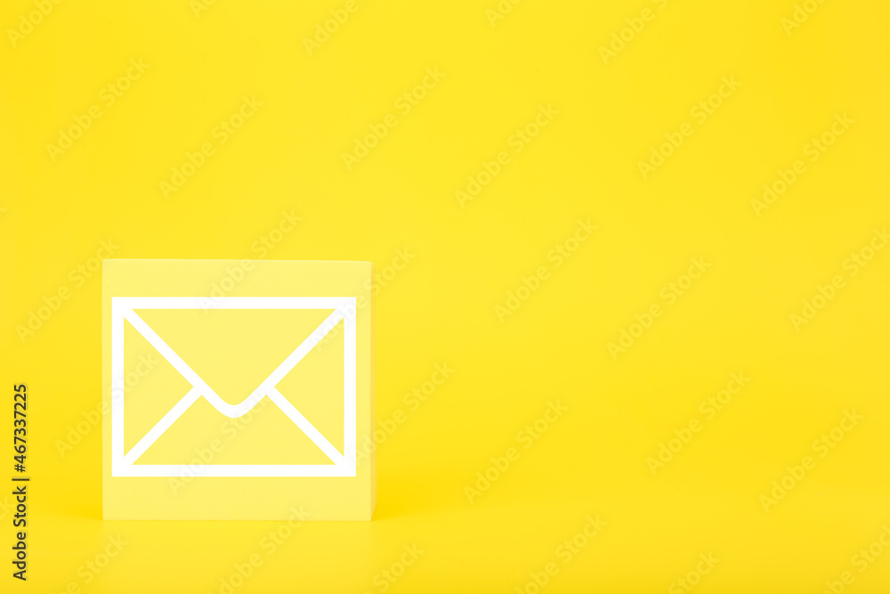 Email marketing or newsletter concept. Envelope drawn on toy square against bright yellow background with copy space