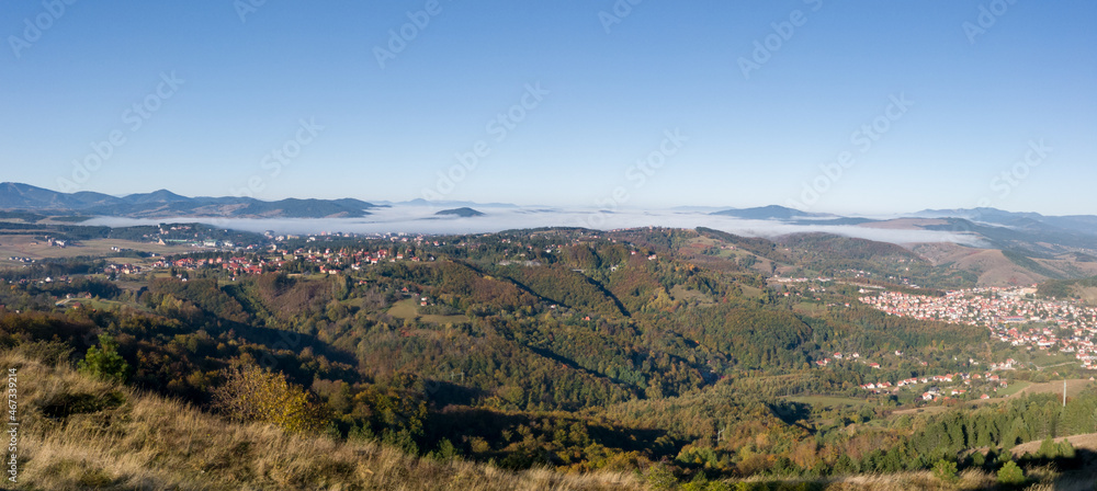 Panoramic view of the forested Zlatibor mountain and parts of the tourist towns of Zlatibor and Cajetina and the nearby peaks that break through the fog in October