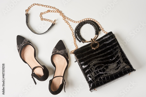 Black leather womens shoes and trendy handbag on white background. Womens accessories. Top view.