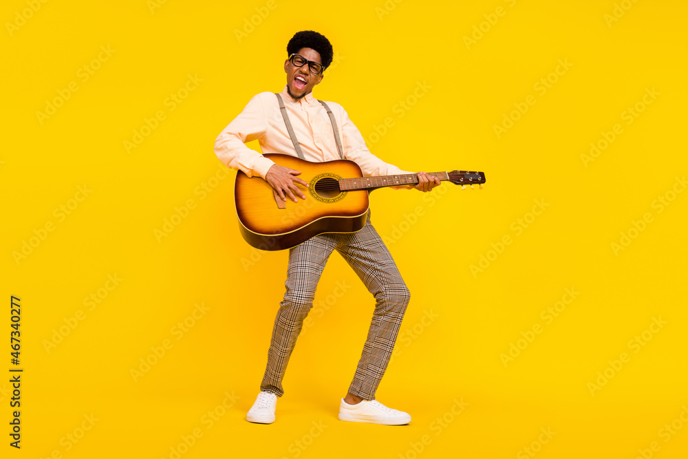 Photo of carefree entertainer guy hold guitar play composition wear suspenders shirt isolated yellow color background