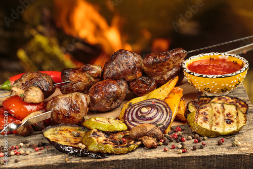 Shashlik or shish kebab preparing on barbecue grill over hot charcoal. Grilled pieces of pork meat on metal skewers. © Victoria