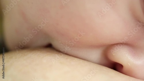 Video of an infant drinking milk. Macro shot of a small caucasian baby eating while on his mother’s hands. Breast feeding. Child eating before an afternoon nap. Cinematic footage of brestfeeding. photo