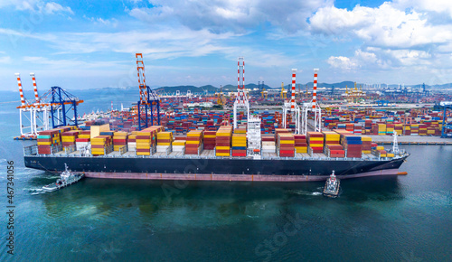 Bird eye view transportation logistics and container dock cargo yard and cargo plane flying with working crane bridge in shipyard with transport logistic import export with blue sky background.