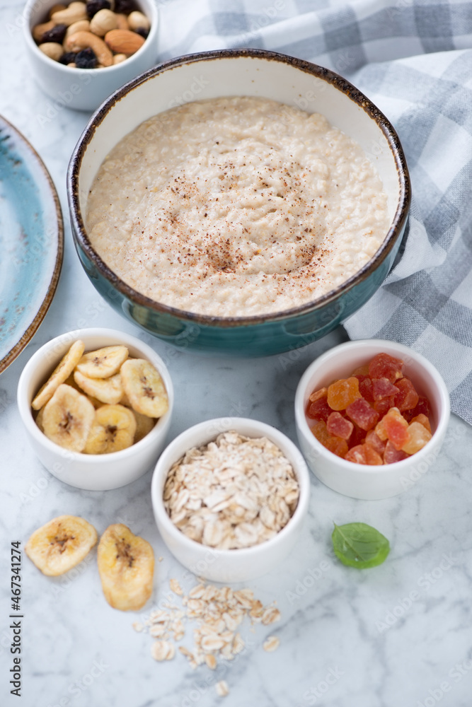 Bowl of oatmeal porridge with various toppings over light-grey marble background, vertical shot Bowl of oatmeal porridge with various toppings over light-grey marble background, vertical shot