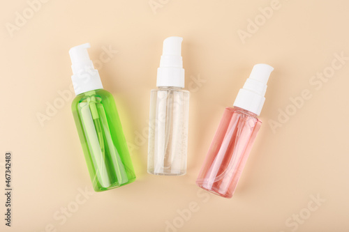 Three different face lotion, liquid foam or gel for skin cleaning in transparent tubes on bright pastel beige background