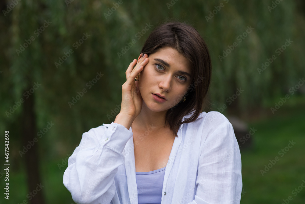 Attractive, happy and stylish brunette Caucasian girl posing in a park in nature. Lifestyle and fashion concept. Attractive, happy and stylish brunette Caucasian girl posing in a park in nature. Lifestyle and fashion concept.