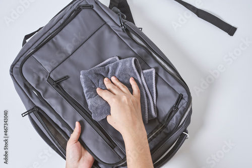 Cleaning backpack with washcloth. A person wipes off dirt or dust from the outside of the bag. Wiping school bag with damp cloth photo