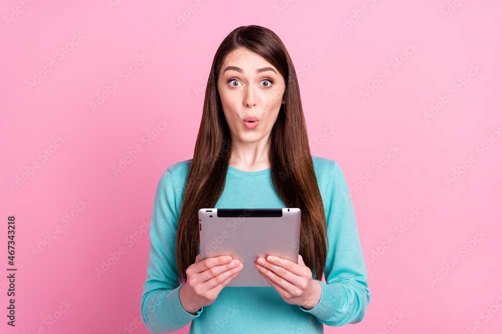 Portrait of attractive amazed funny girl holding in hands ebook pout lips news isolated over pink pastel color background Portrait of attractive amazed funny girl holding in hands ebook pout lips news isolated over pink pastel color background