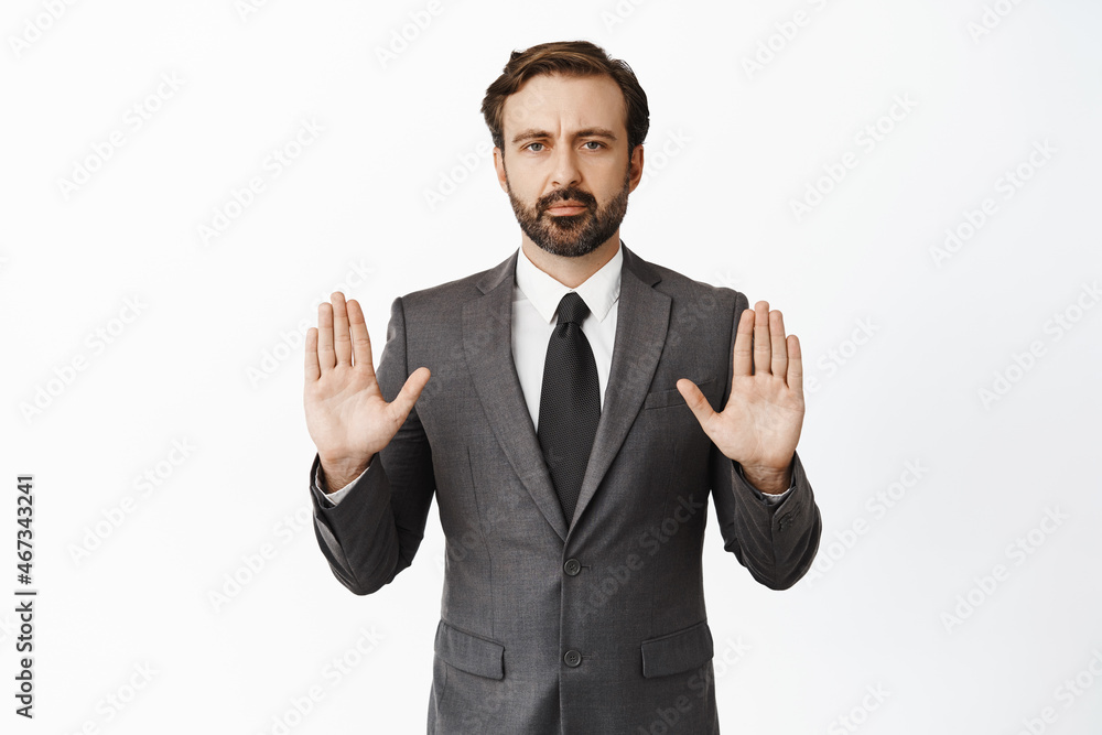 Stop. taboo gesture. Portrait of businessman showing warning gesture, extending hands and saying no, prohibit action, wearing suit, white background Stop. taboo gesture. Portrait of businessman showing warning gesture, extending hands and saying no, prohibit action, wearing suit, white background