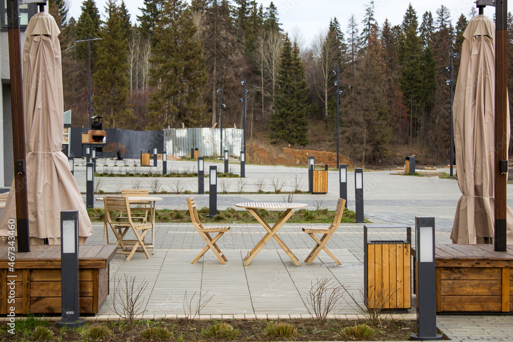 An empty outdoor cafe with wooden furniture An empty outdoor cafe with wooden furniture