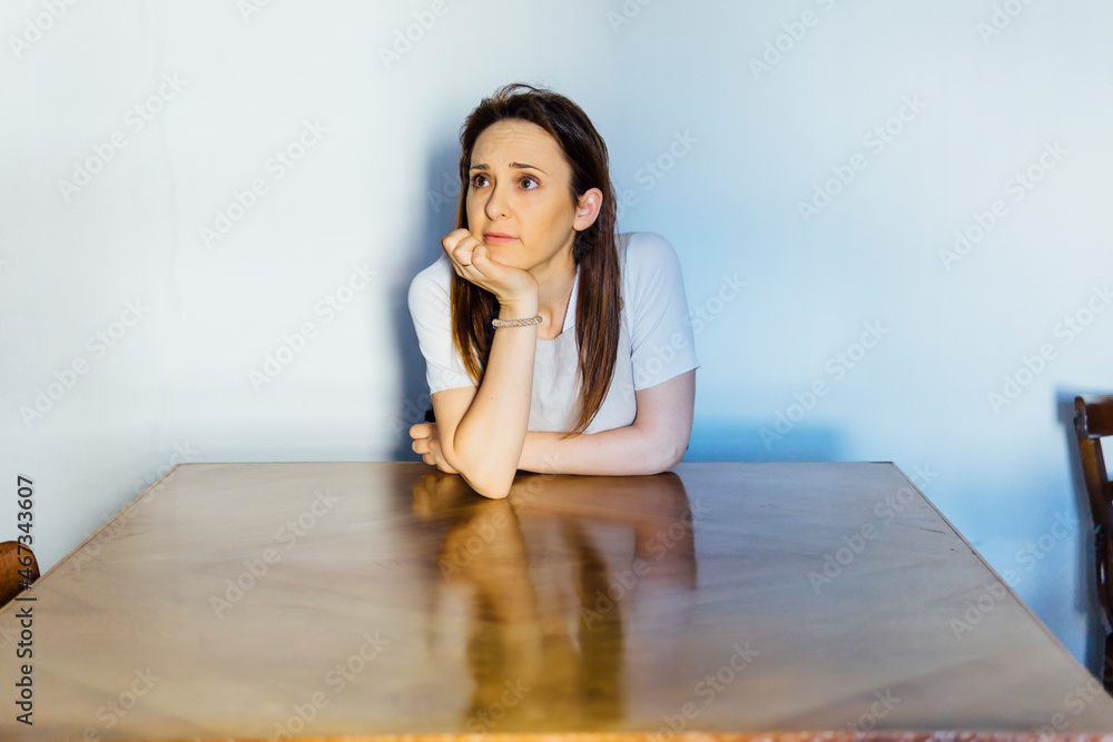 beautiful young middle-aged woman sitting at a table thoughtfully. reflection concept. beautiful young middle-aged woman sitting at a table thoughtfully. reflection concept.