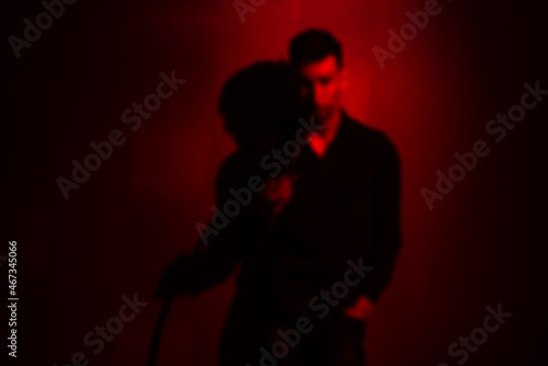silhouette of a man in red light with a hookah pipe out of focus