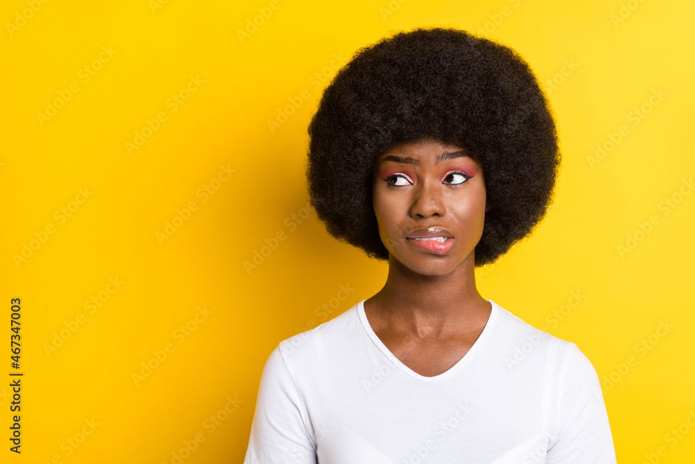 Photo of unhappy troubled young dark skin woman look empty space bite lip isolated on yellow color background Photo of unhappy troubled young dark skin woman look empty space bite lip isolated on yellow color background