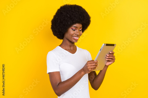 Photo of positive nice afro american young woman look hold tablet isolated on shine yellow color background