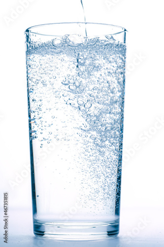 mineral water pours into a glass on a white background