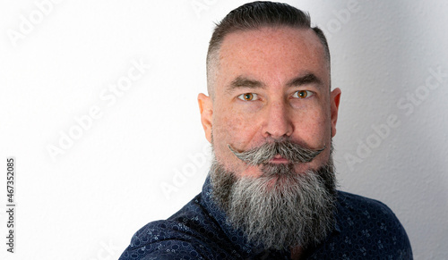 close-up of hipster style man, big beard half-gray and honey-colored eyes