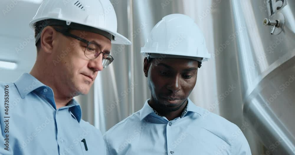 Two Industry Engineers Walk in Factory, Use Tablet and Discuss Work Two Industry Engineers Walk in Factory, Use Tablet and Discuss Work