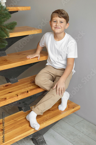 Minimalistic studio photo of eight old caucasian boy wearing in white t-shirt and beige pants for creating mockups for presentation graphic tees and pattern design