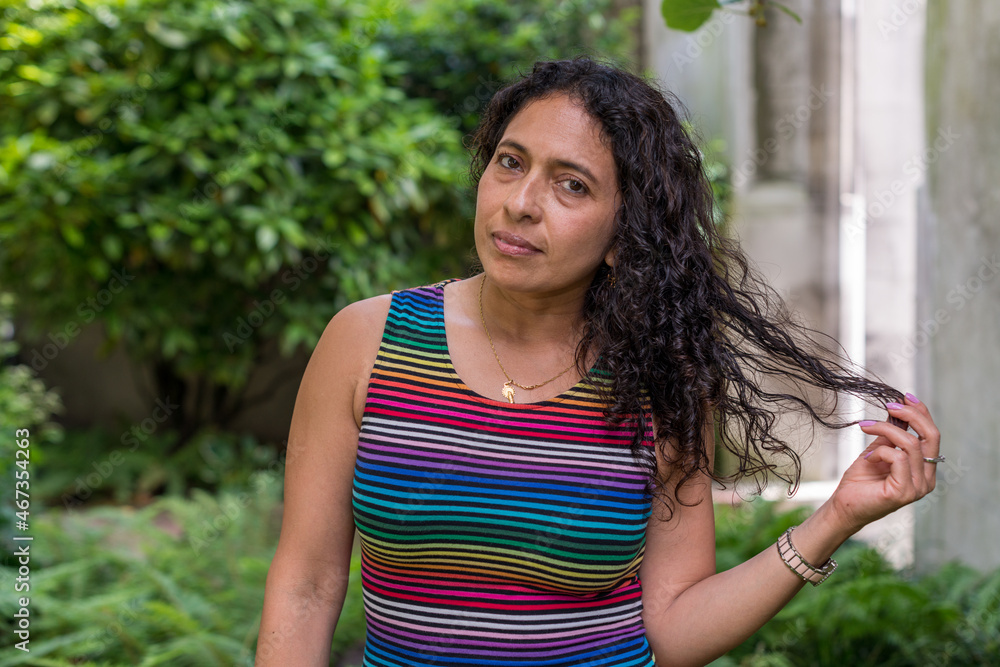 Portrait of Latin woman with wavy hair wearing striped clothes and looking at the camera Portrait of Latin woman with wavy hair wearing striped clothes and looking at the camera