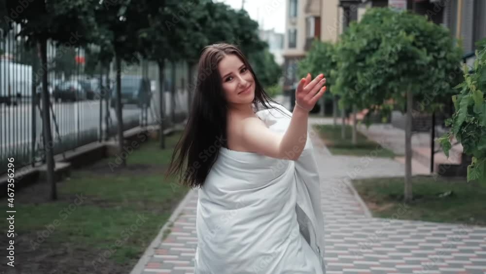 pretty girl in a white blanket walking by the street. slow motion. pretty girl in a white blanket walking by the street. slow motion.
