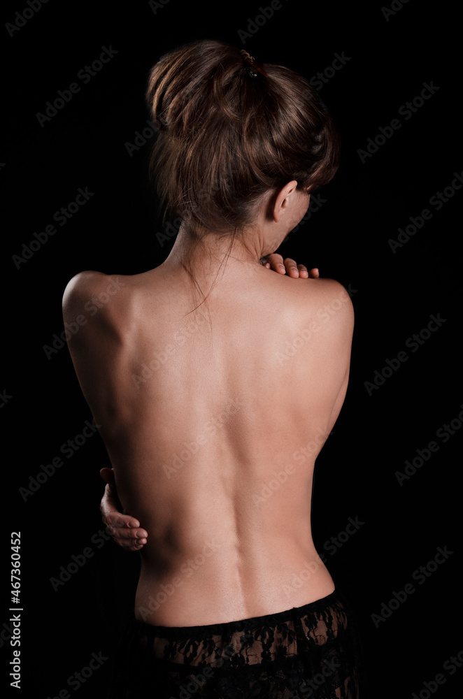 Rear view at topless brunette caucasian model in black underwear on dark background Rear view at topless brunette caucasian model in black underwear on dark background