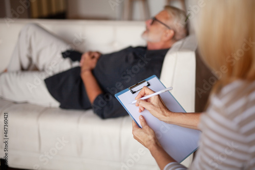 The psychologist writes, the patient is to lie down. Senior man with anxiety, consultation with a doctor. photo