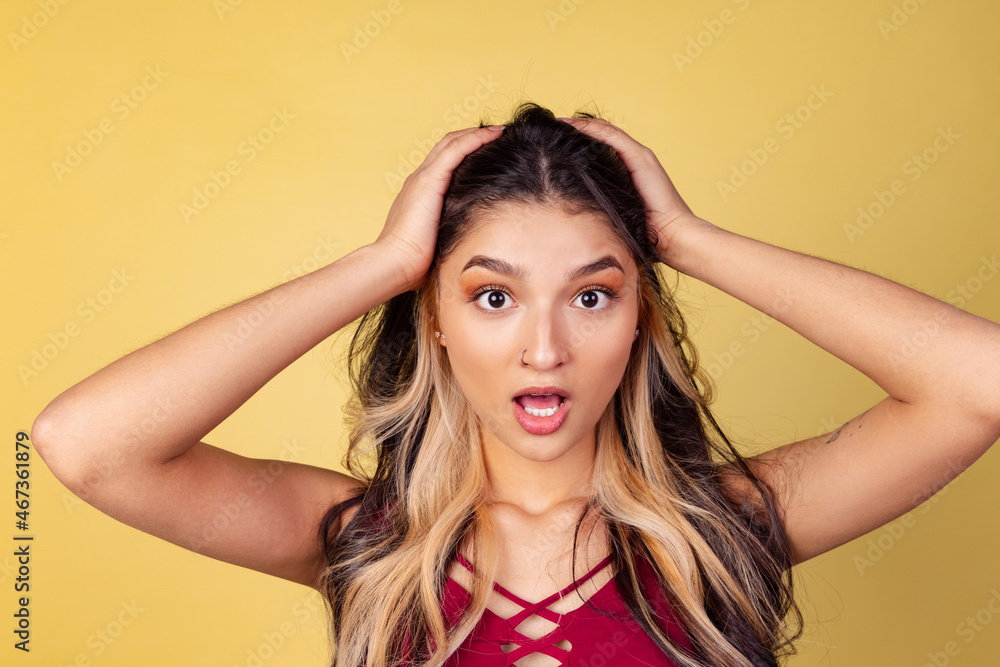 Portrait of young beuatiful girl, student in bright red top open her mouth isolated on yellow studio backgroud.