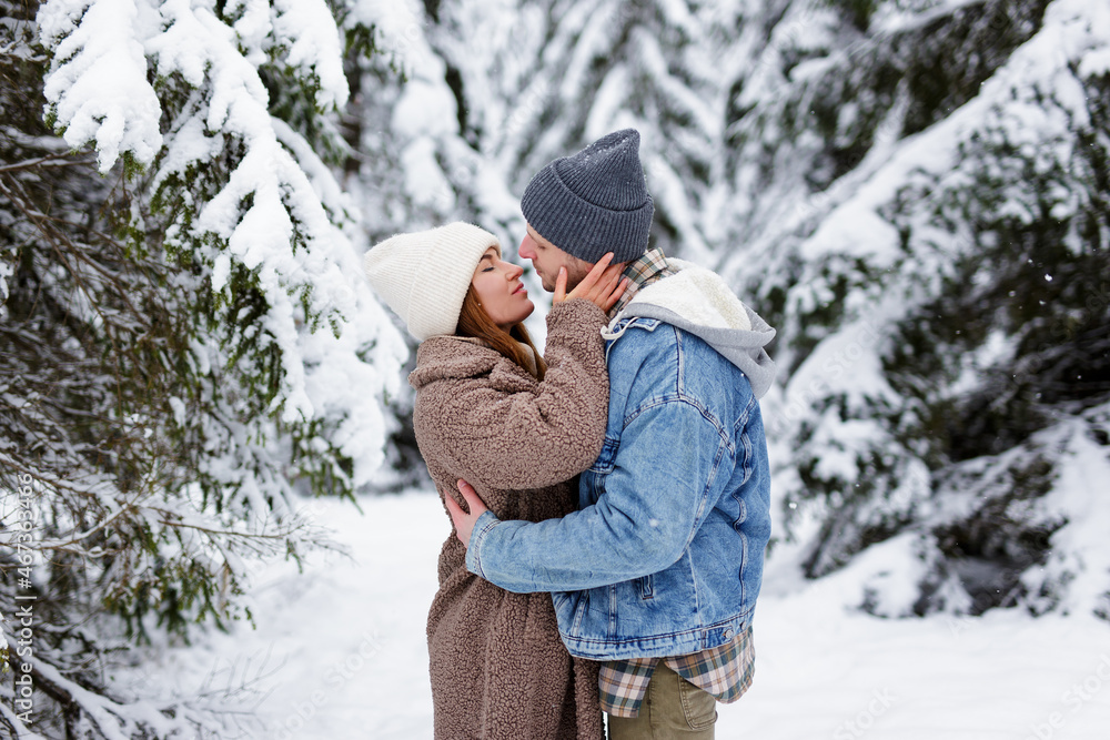 love and romance concept - man and woman kissing in winter forest